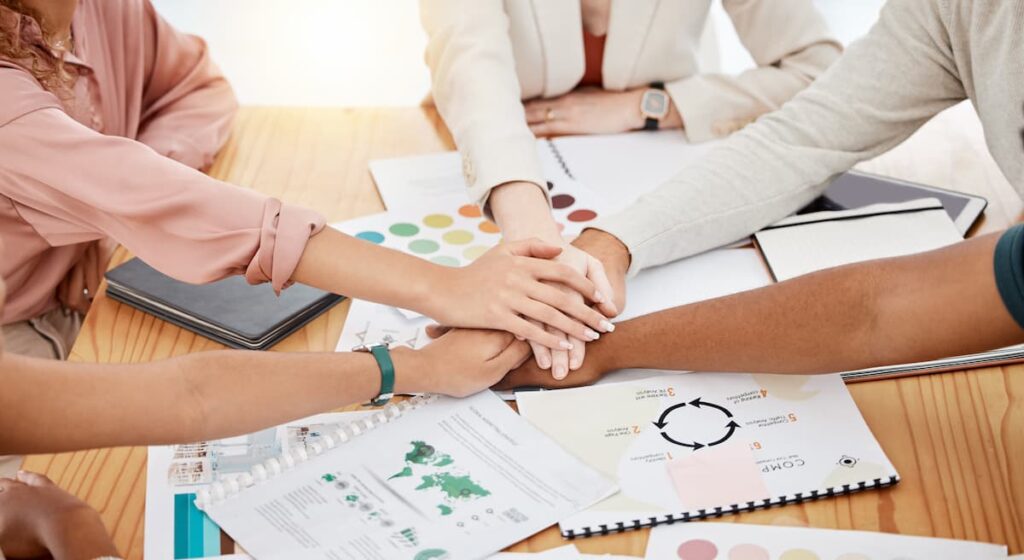 workers joining hands on a desk